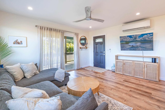 living room with a wall mounted air conditioner, ceiling fan, and light wood-type flooring