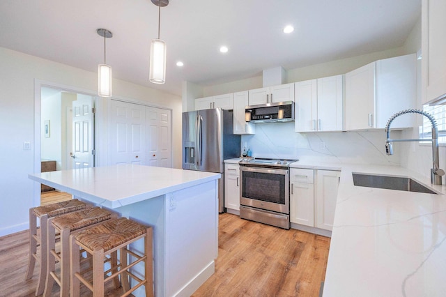 kitchen with tasteful backsplash, white cabinetry, sink, hanging light fixtures, and stainless steel appliances