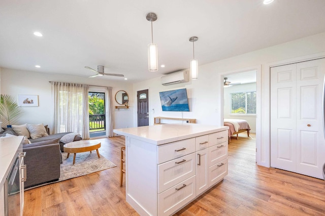 kitchen with pendant lighting, a wall mounted air conditioner, light hardwood / wood-style flooring, and white cabinets