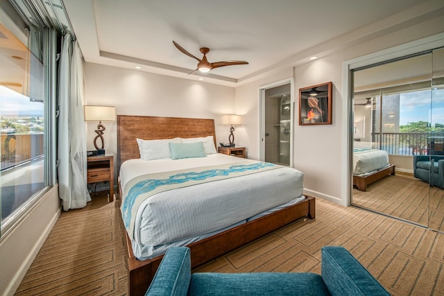 bedroom with ceiling fan, carpet, ensuite bathroom, and a tray ceiling