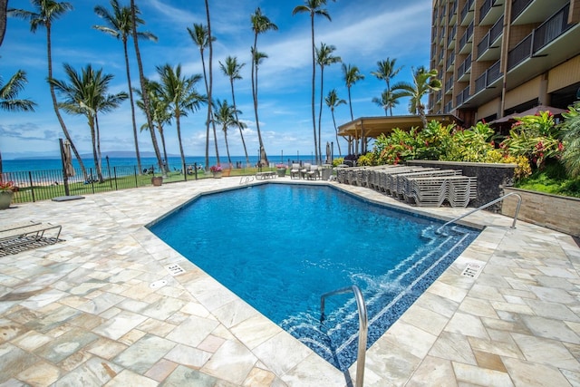 view of pool featuring a patio and a water view