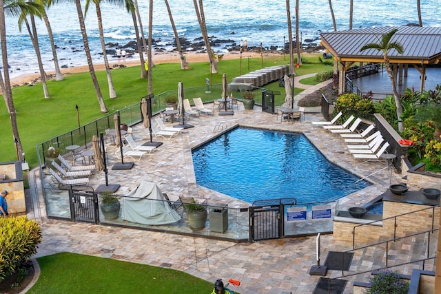 view of pool with a beach view, a yard, a water view, and a patio