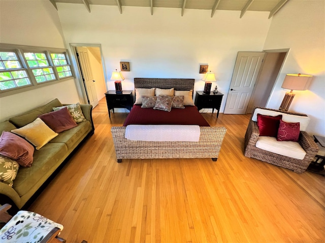 bedroom with light hardwood / wood-style floors and beam ceiling