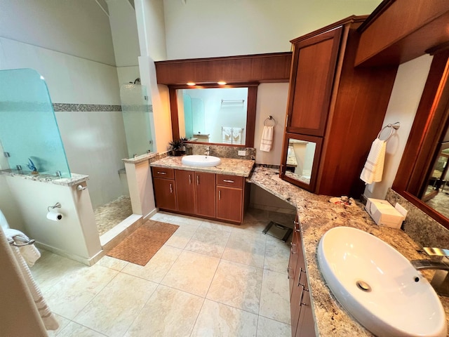 bathroom with vanity, a tile shower, and tile patterned flooring