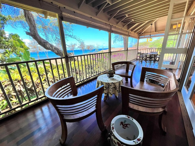 sunroom / solarium featuring a water view, a healthy amount of sunlight, and vaulted ceiling