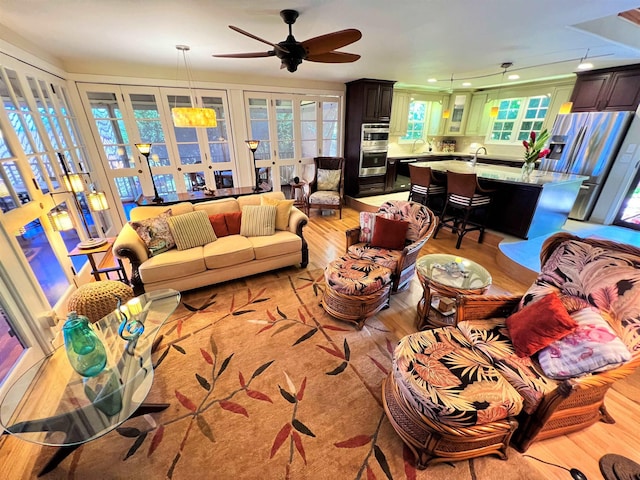 living room with ceiling fan, sink, and light wood-type flooring