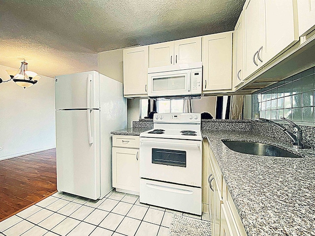 kitchen featuring white appliances, sink, light hardwood / wood-style flooring, a textured ceiling, and white cabinetry