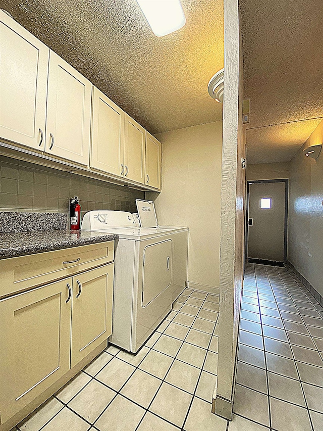 laundry room featuring washing machine and dryer, light tile patterned floors, cabinets, and a textured ceiling