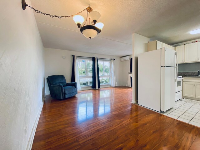 kitchen with light hardwood / wood-style flooring, a notable chandelier, an AC wall unit, white appliances, and white cabinets