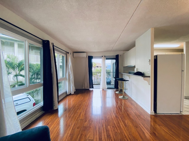 unfurnished living room featuring a textured ceiling, a wall unit AC, and dark hardwood / wood-style floors