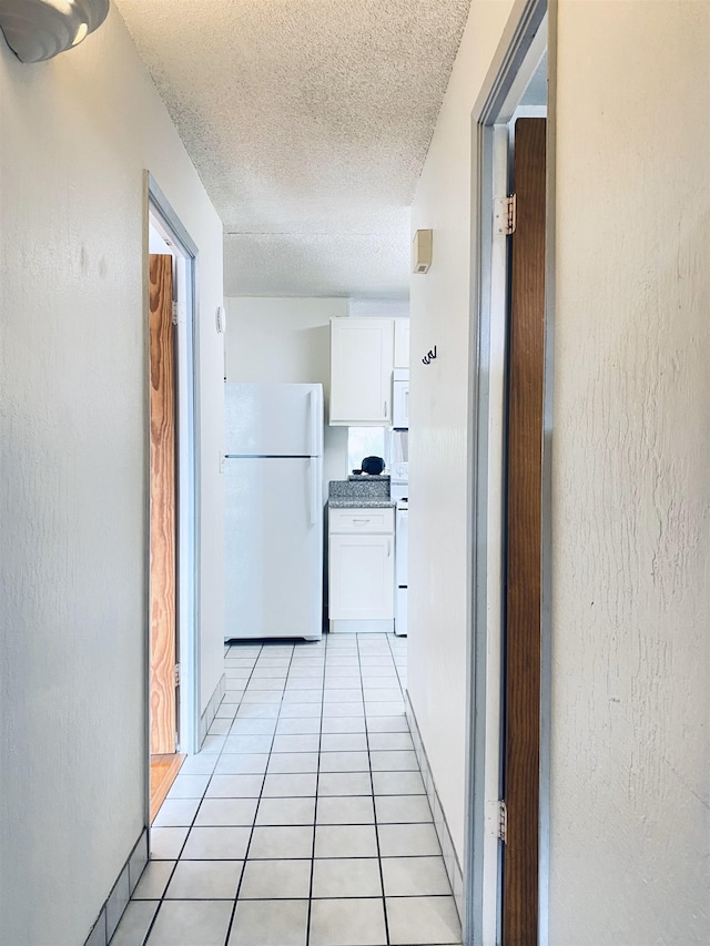 hallway featuring light tile patterned floors and a textured ceiling