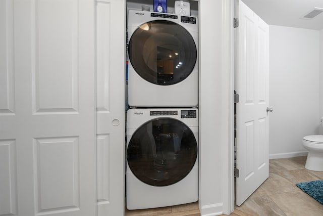 washroom featuring stacked washer / dryer and light tile patterned floors