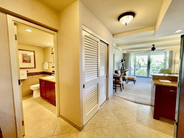 hallway with sink, light tile patterned flooring, and tile walls