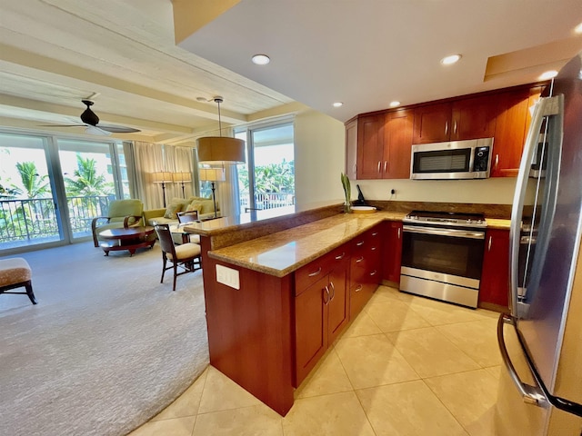 kitchen featuring light stone countertops, appliances with stainless steel finishes, light carpet, decorative light fixtures, and kitchen peninsula