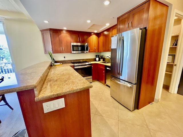 kitchen with light stone countertops, appliances with stainless steel finishes, light tile patterned floors, sink, and kitchen peninsula