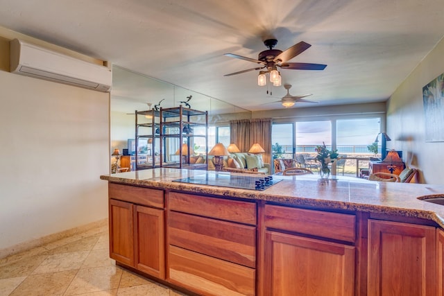 4909 Lower Honoapiilani Rd Unit A8, Lahaina, HI 96761 - kitchen with an AC wall unit, black electric stovetop, brown cabinetry, a ceiling fan, and baseboards