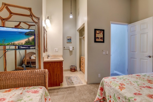 carpeted bedroom featuring ensuite bath, sink, and a high ceiling