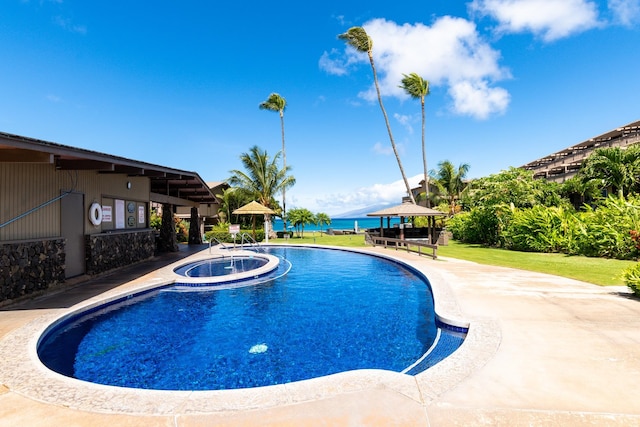 view of swimming pool with a gazebo, an in ground hot tub, a yard, and a water view