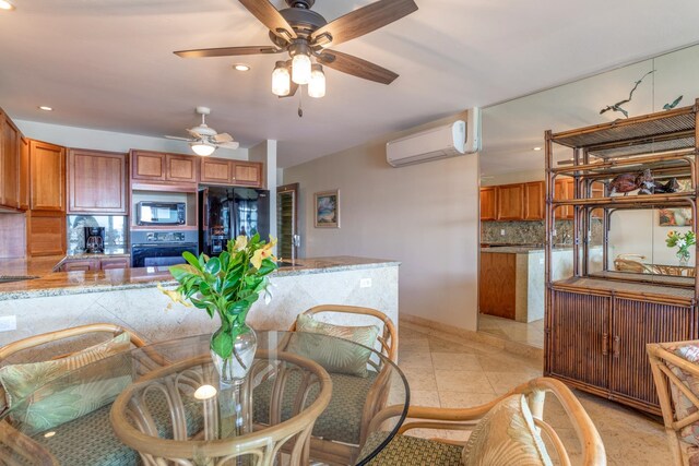 kitchen with backsplash, light stone counters, an AC wall unit, and black appliances