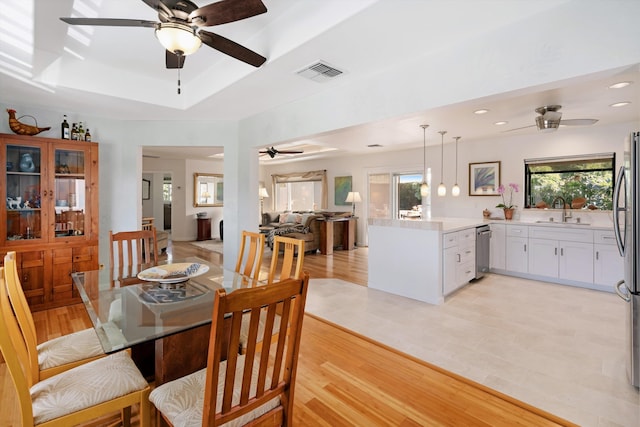 dining space featuring a wealth of natural light, visible vents, light wood finished floors, and a tray ceiling