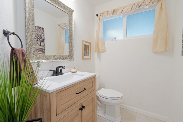 half bath featuring tile patterned flooring, toilet, vanity, and baseboards