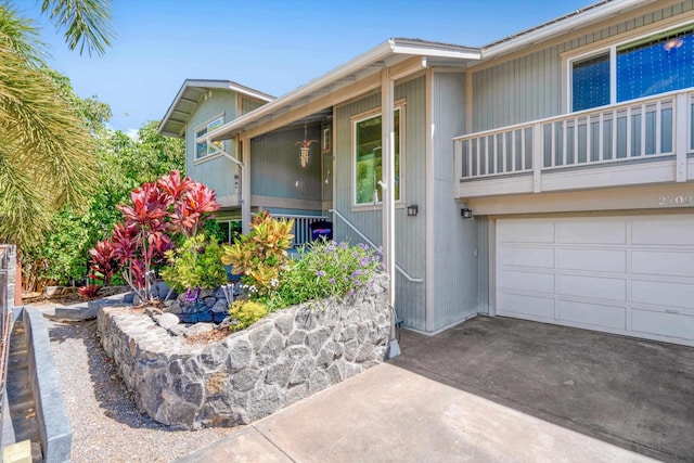 property entrance with a garage, driveway, and a balcony