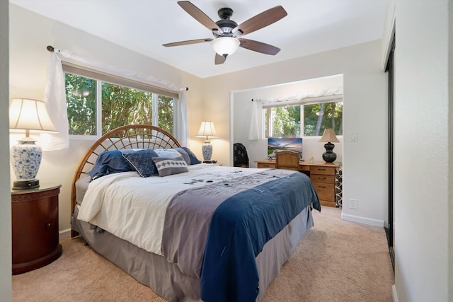 bedroom with light colored carpet, a ceiling fan, and baseboards