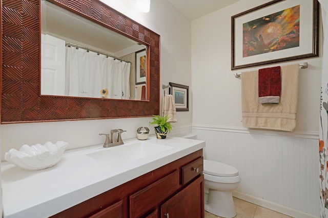 bathroom with tile patterned floors, vanity, toilet, and wainscoting