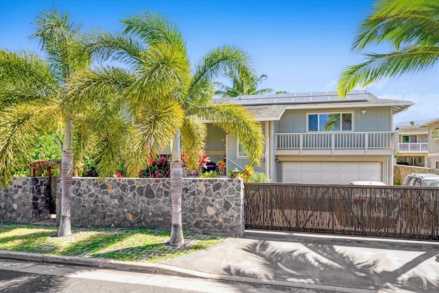 view of front of property with a fenced front yard, roof mounted solar panels, driveway, and a garage