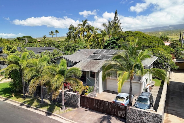 view of front of home with fence, driveway, solar panels, stucco siding, and a shingled roof