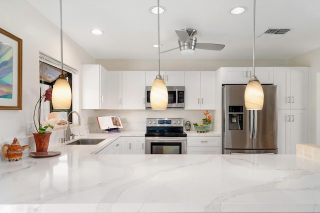 kitchen with visible vents, light stone counters, white cabinets, stainless steel appliances, and a sink