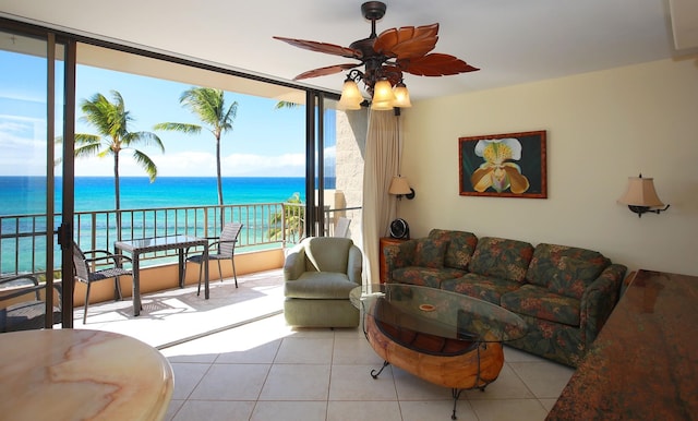 living room featuring a wealth of natural light, ceiling fan, a water view, and light tile patterned flooring