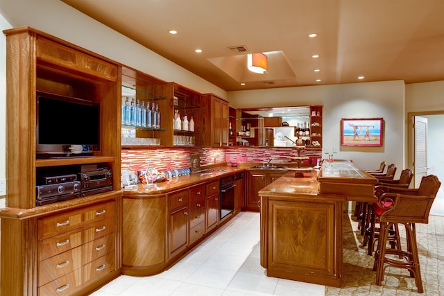 kitchen with sink, black oven, backsplash, a center island, and kitchen peninsula