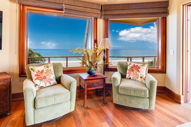 sitting room with hardwood / wood-style flooring and a water view