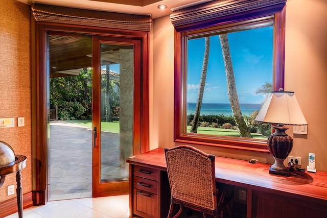 home office featuring light tile patterned flooring, a water view, and built in desk