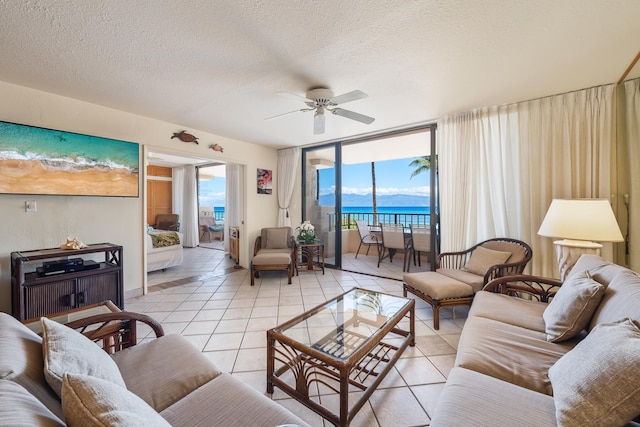 living room featuring a healthy amount of sunlight, a water view, light tile patterned floors, and ceiling fan