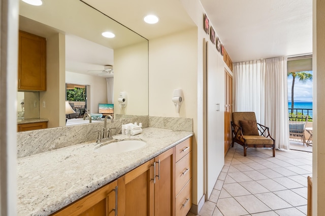 bathroom with a water view, tile patterned flooring, vanity, and ceiling fan