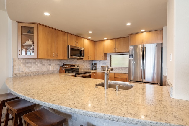 kitchen featuring a kitchen breakfast bar, backsplash, kitchen peninsula, stainless steel appliances, and sink