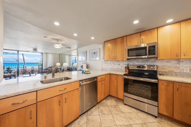 kitchen featuring appliances with stainless steel finishes, tasteful backsplash, kitchen peninsula, ceiling fan, and sink