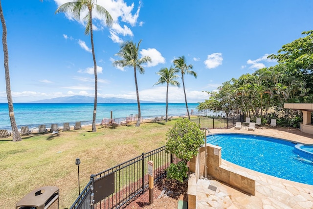 view of pool with a patio, a yard, and a water view