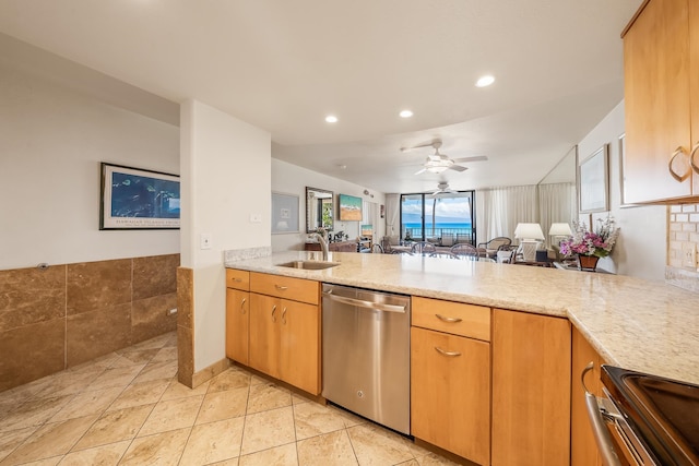 kitchen featuring light stone counters, sink, kitchen peninsula, stainless steel appliances, and ceiling fan