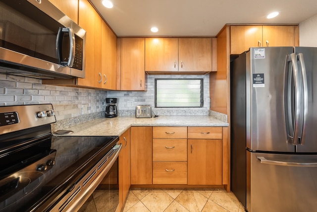 kitchen featuring light stone counters, appliances with stainless steel finishes, and tasteful backsplash