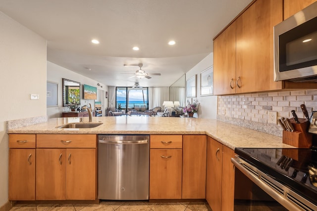 kitchen with ceiling fan, stainless steel appliances, sink, and kitchen peninsula