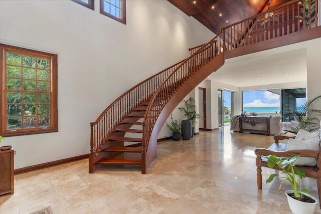 stairs with light tile floors, wooden ceiling, a towering ceiling, and a water view