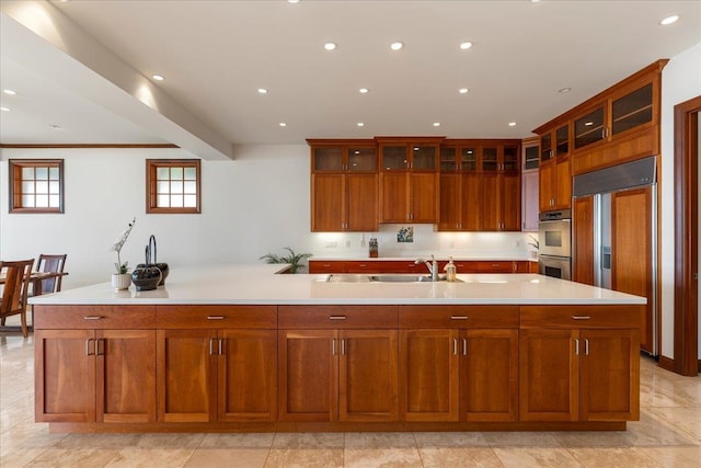 kitchen featuring stainless steel double oven, an island with sink, paneled refrigerator, and light tile floors