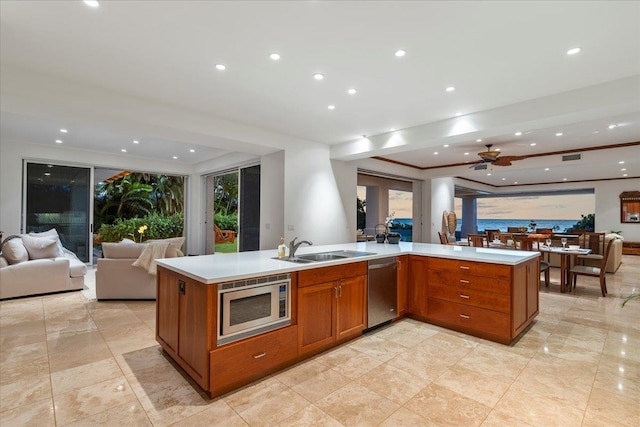 kitchen featuring an island with sink, stainless steel appliances, ceiling fan, and sink