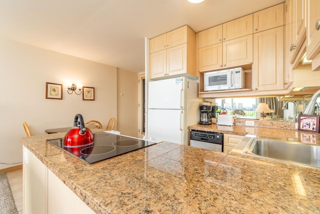 kitchen with kitchen peninsula, white appliances, sink, cream cabinetry, and light tile patterned flooring