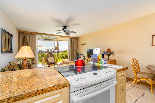 kitchen featuring electric range, light brown cabinetry, ceiling fan, and light tile patterned flooring