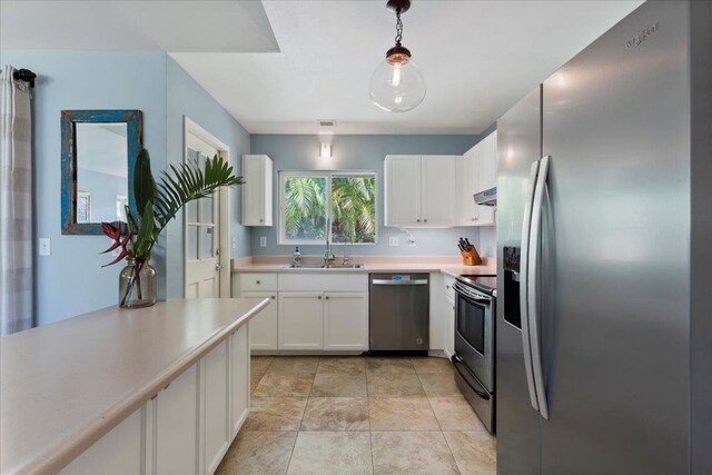 kitchen with hanging light fixtures, sink, stainless steel appliances, and white cabinetry