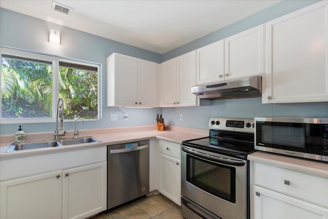 kitchen with light tile patterned floors, sink, white cabinets, and stainless steel appliances